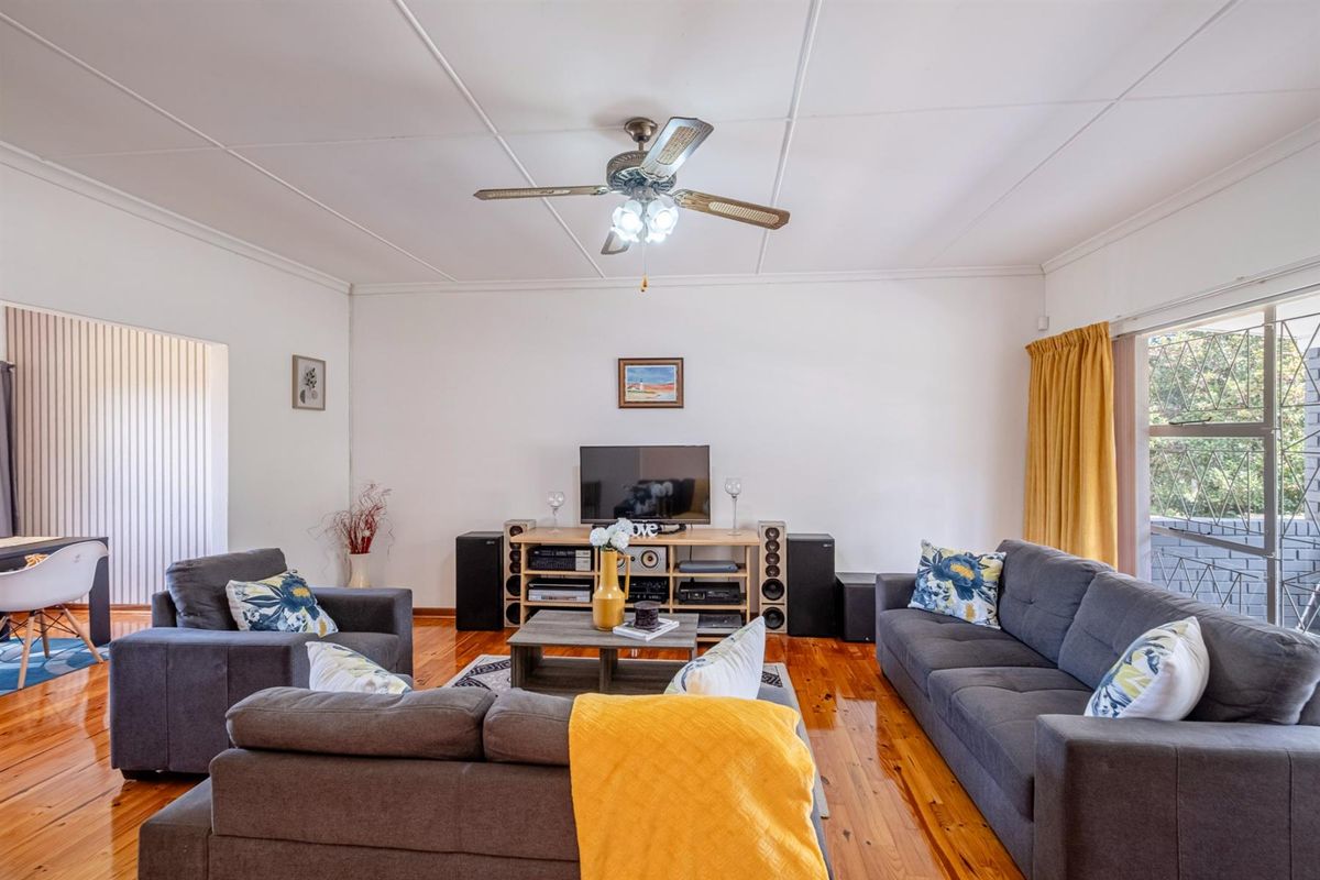 A comfortable living room featuring polished hardwood flooring, a ceiling fan, and a sliding glass door providing access to the exterior.