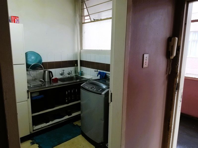 A functional laundry area featuring a stainless steel sink, tiled splashback, and dedicated plumbing connections for a washing machine.