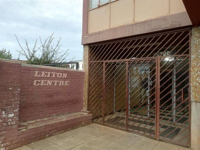 Front entrance of Leiton Centre featuring a security gate, brick boundary wall, and paved walkway access.