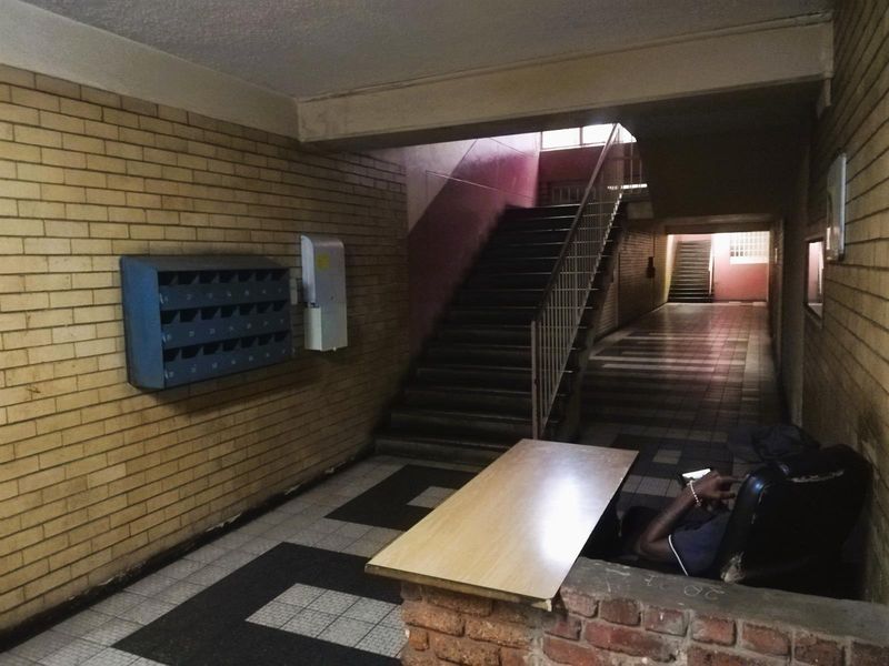 Communal apartment building entrance lobby featuring a staircase, brick walls, and a bank of mailboxes with tiled flooring.