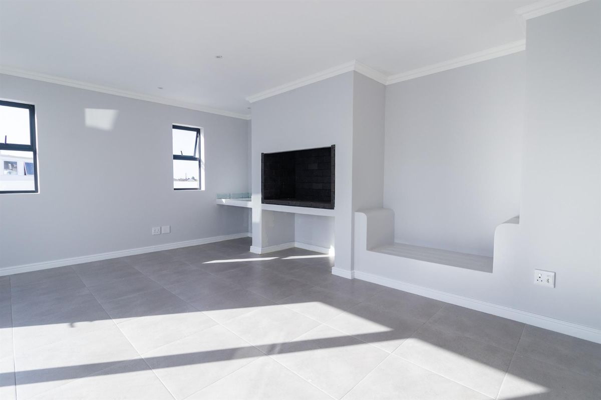 A bright, empty living room featuring neutral tiled flooring, a built-in fireplace, and a custom built-in bench, offering a clean and modern aesthetic.