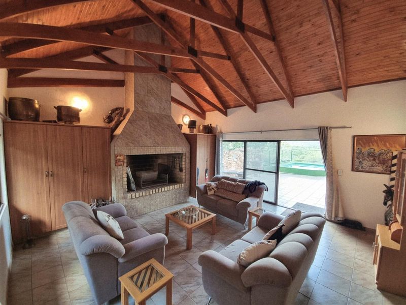 Spacious living room featuring a high vaulted timber ceiling with exposed trusses, a large built-in fireplace, and sliding glass doors leading to the patio.