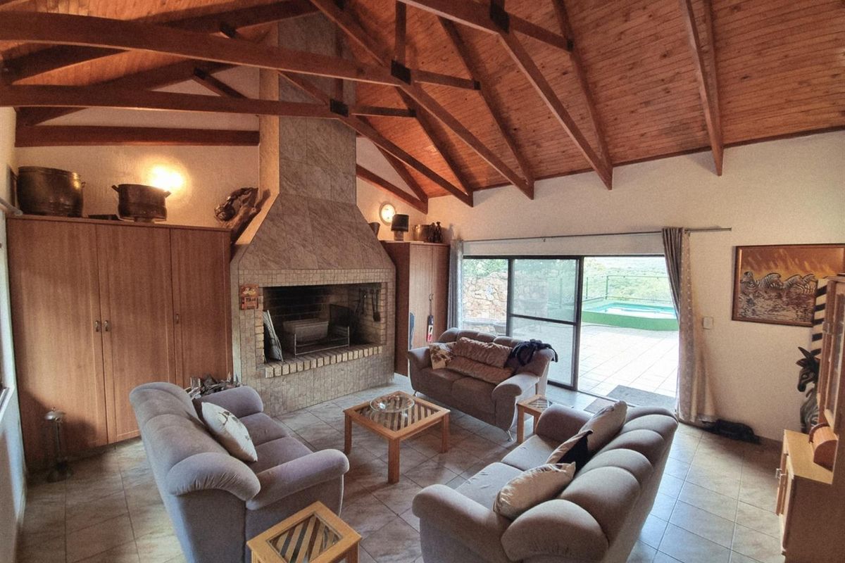 Spacious living room featuring a high vaulted timber ceiling with exposed trusses, a large built-in fireplace, and sliding glass doors leading to the patio.
