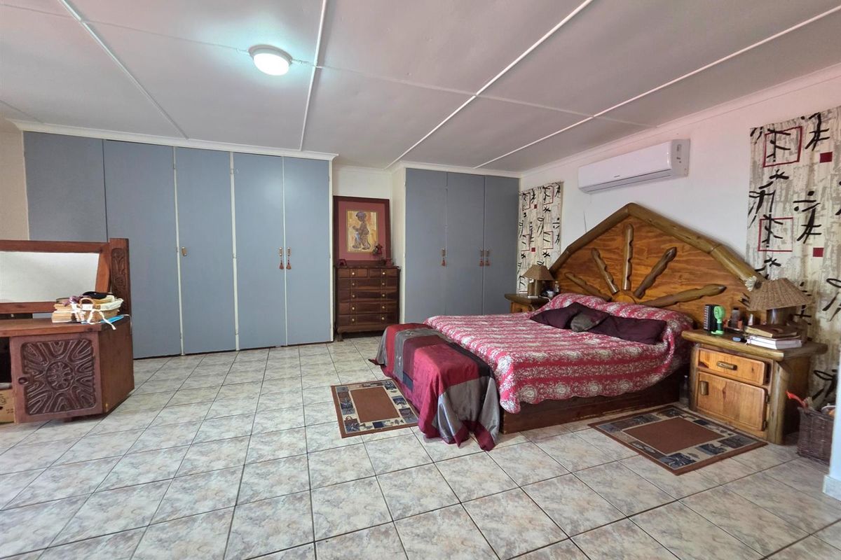 Spacious bedroom featuring extensive built-in cupboard storage, tiled flooring, and a wall-mounted air conditioning unit.