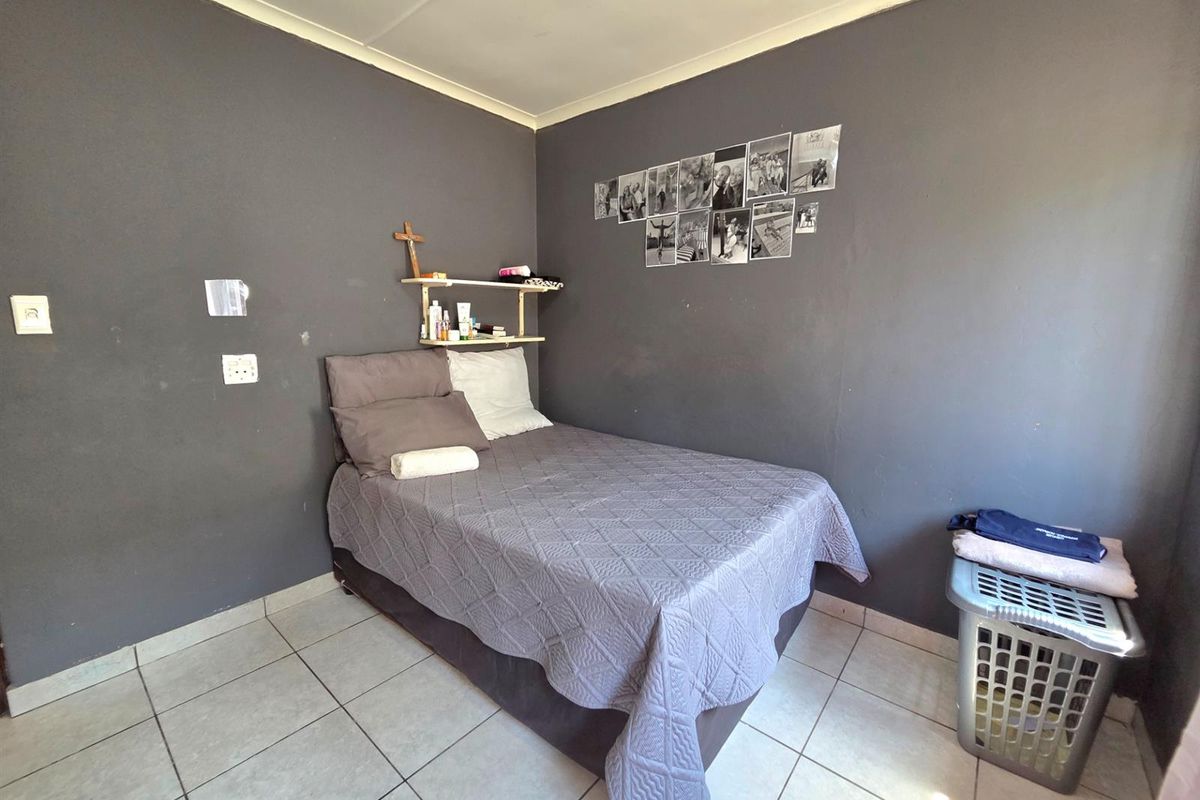 A compact bedroom featuring tiled flooring and dark grey painted walls, offering a functional space ready for cosmetic updates.