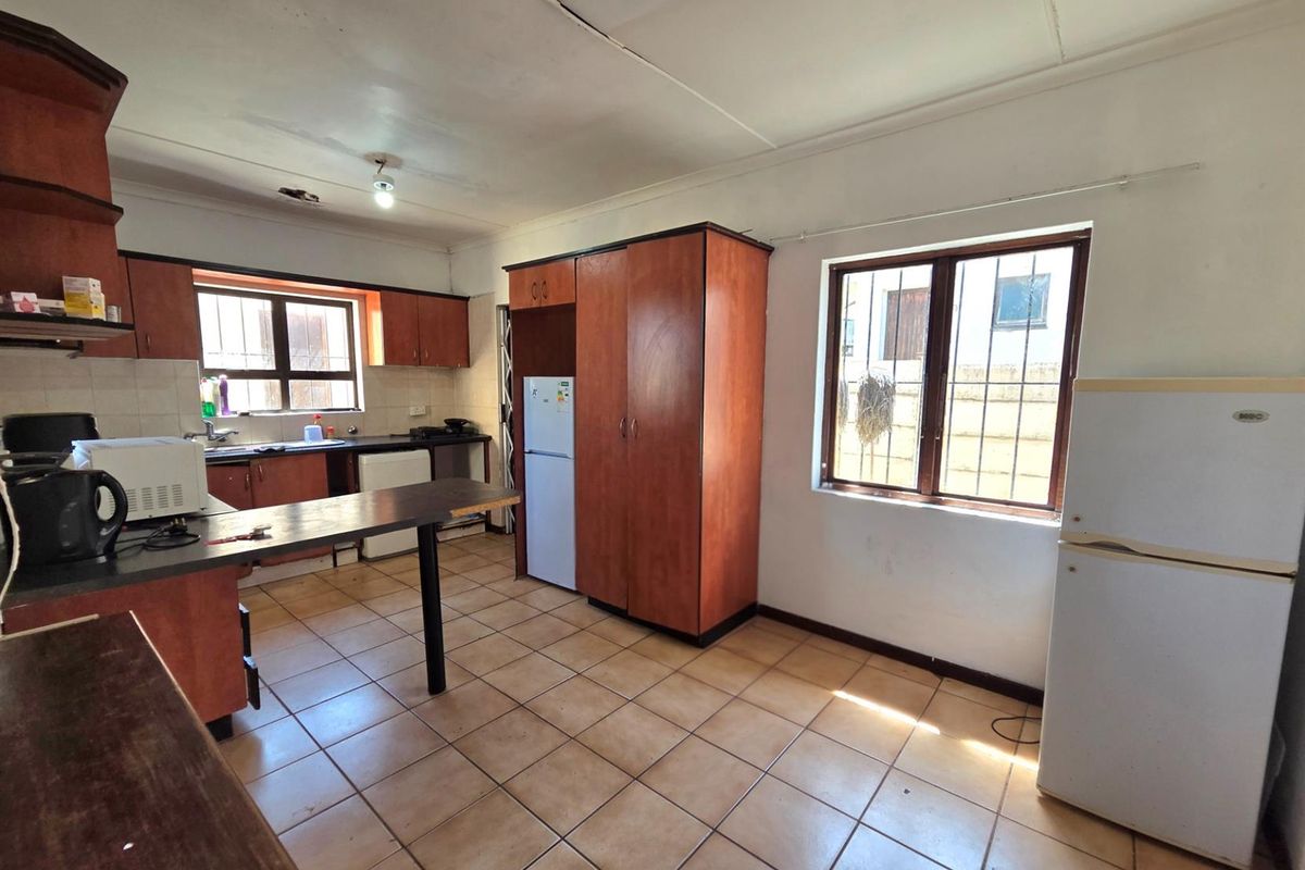 A functional kitchen featuring tiled flooring, laminate cabinetry, a breakfast bar, and a built-in pantry, offering potential for modernization and cosmetic updates.