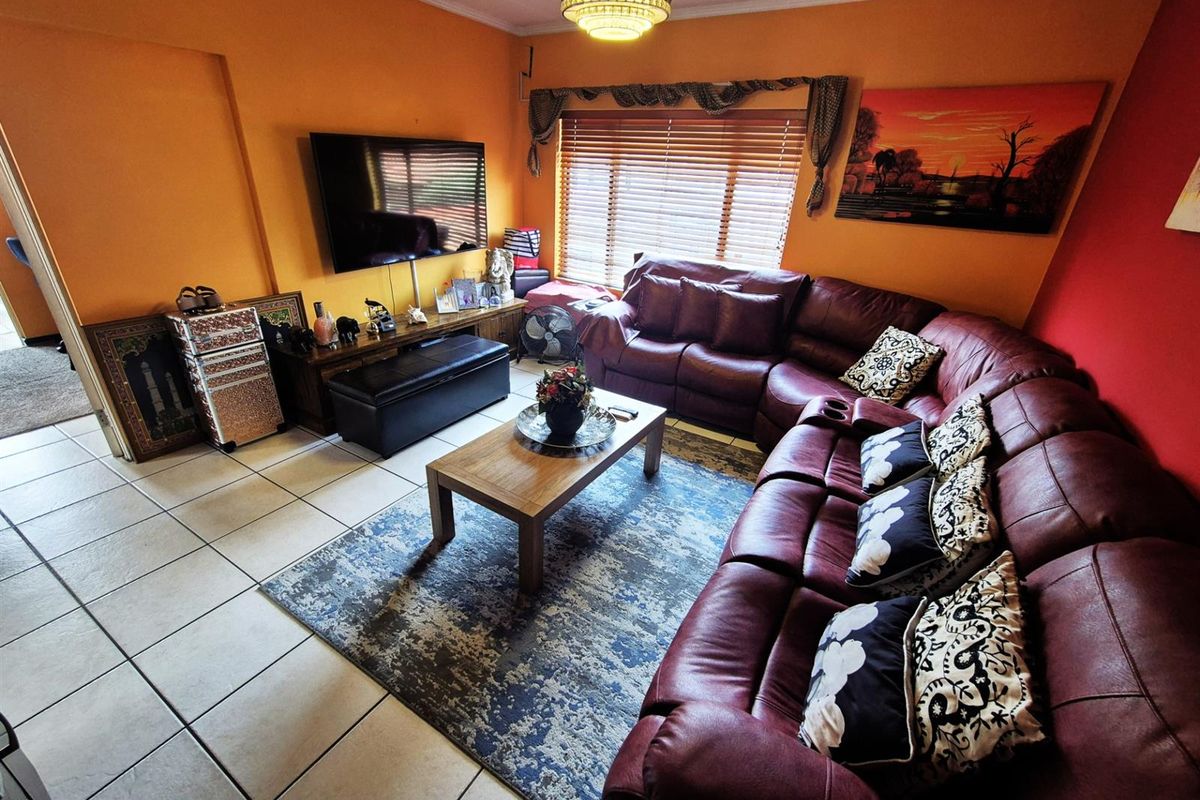 A living room featuring tiled flooring, a ceiling-mounted light fixture, and window blinds.