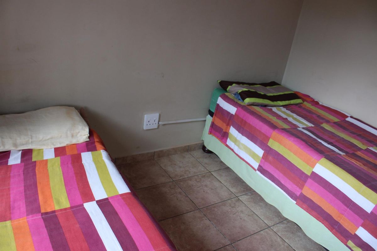 A bedroom featuring tiled flooring and a wall-mounted electrical outlet with surface-mounted conduit.