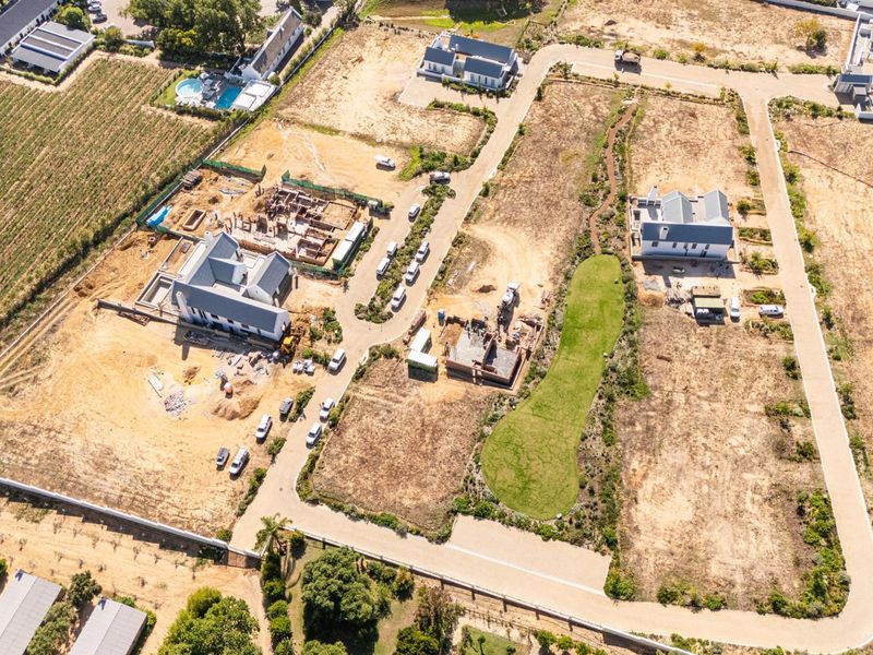 Aerial view of a residential development estate featuring multiple plots, some with completed homes and others currently under construction.