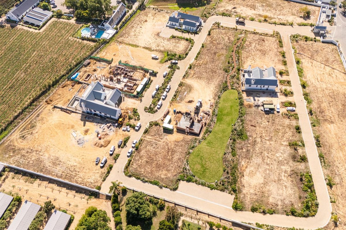 Aerial view of a residential development estate featuring multiple plots, some with completed homes and others currently under construction.