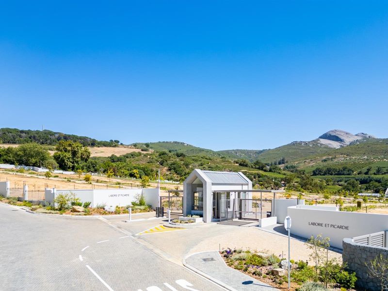 A view of the secure entrance gatehouse and perimeter walling for the Laborie et Picardie residential estate, set against a scenic mountain backdrop.