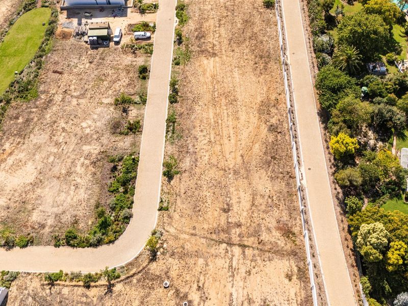An aerial view of a vacant residential plot featuring established paved access roads and boundary fencing, ready for development.