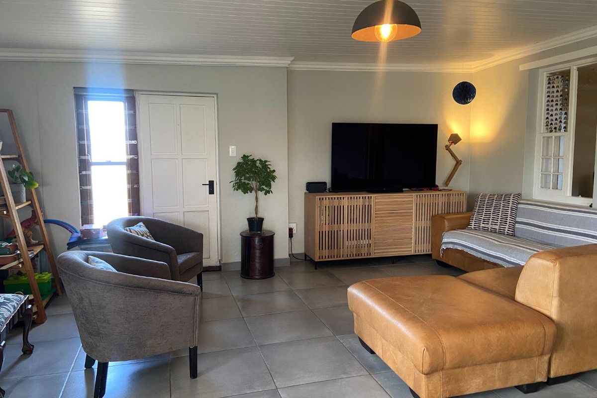 A comfortable living room featuring tiled flooring, a tongue-and-groove ceiling, and a panelled door leading to the exterior.