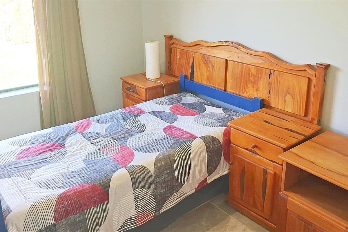 A bedroom featuring tiled flooring and a window with curtains, providing a functional and neutral living space.
