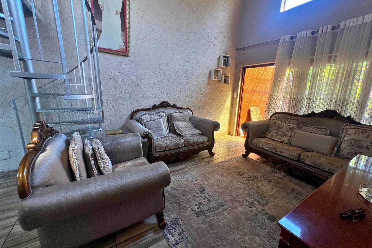 Spacious living room featuring a double-volume ceiling, a metal spiral staircase, and large windows allowing for natural light.