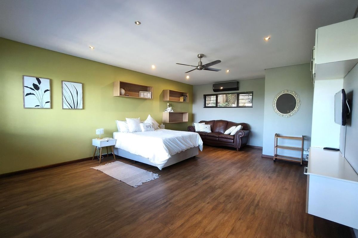 Spacious bedroom featuring wood-look flooring, recessed ceiling lighting, a ceiling fan, and a wall-mounted air conditioning unit.