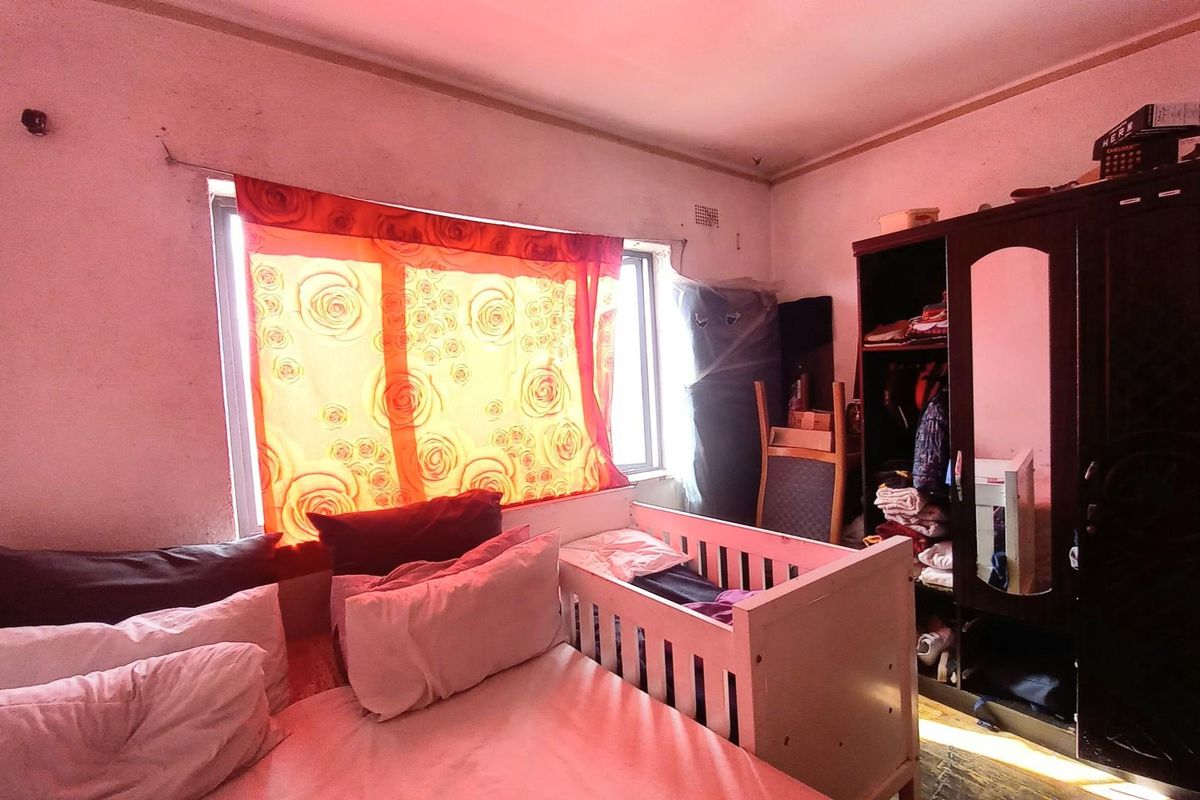 A bedroom featuring a window with natural light, built-in wardrobe space, and standard flooring, requiring cosmetic updates to improve the overall finish.