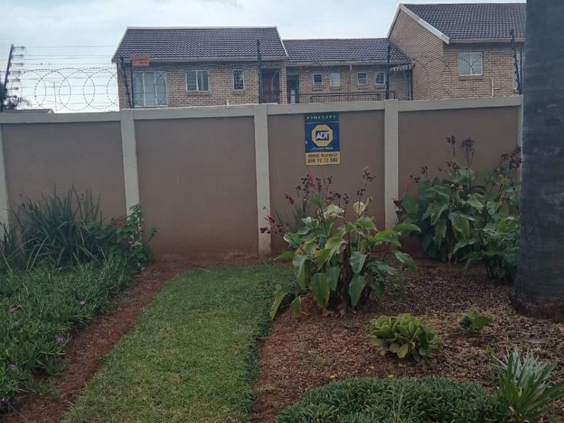 A private rear garden area featuring a perimeter wall with integrated electric fencing and established garden beds.