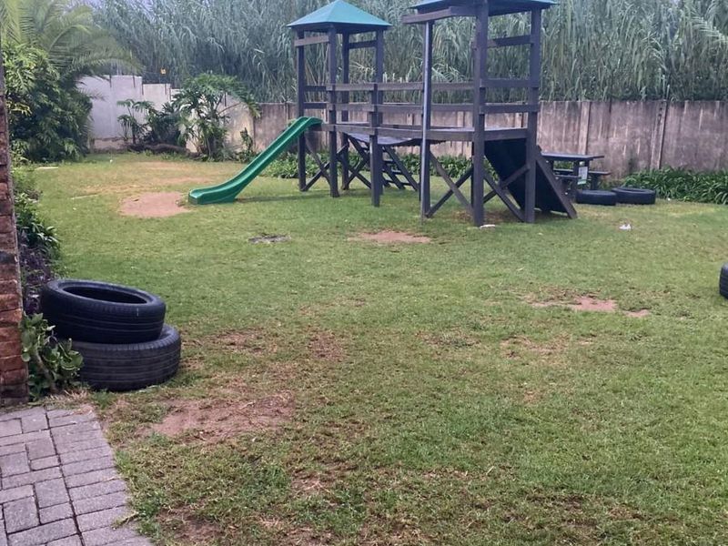 A private garden area featuring a lawn, paved walkway, and perimeter wall, providing an outdoor space for recreation.