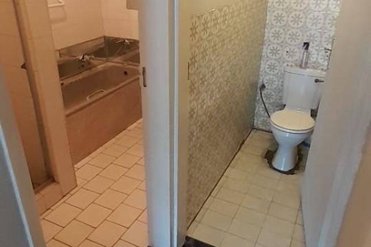 A functional bathroom layout featuring a separate toilet area and a main bathroom with a built-in bathtub and tiled finishes.