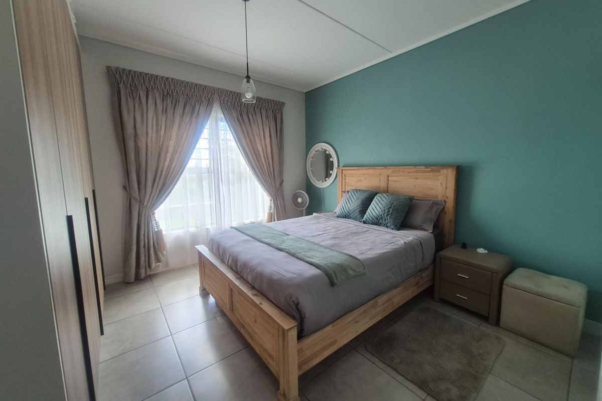 A well-maintained bedroom featuring tiled flooring, a built-in wardrobe, and a feature wall, offering a comfortable and functional living space.