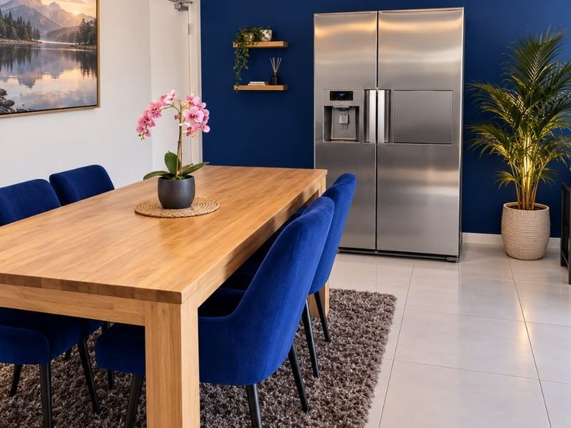 A modern dining area featuring tiled flooring, a contemporary pendant light fixture, and stylish floating shelves against a bold blue accent wall.