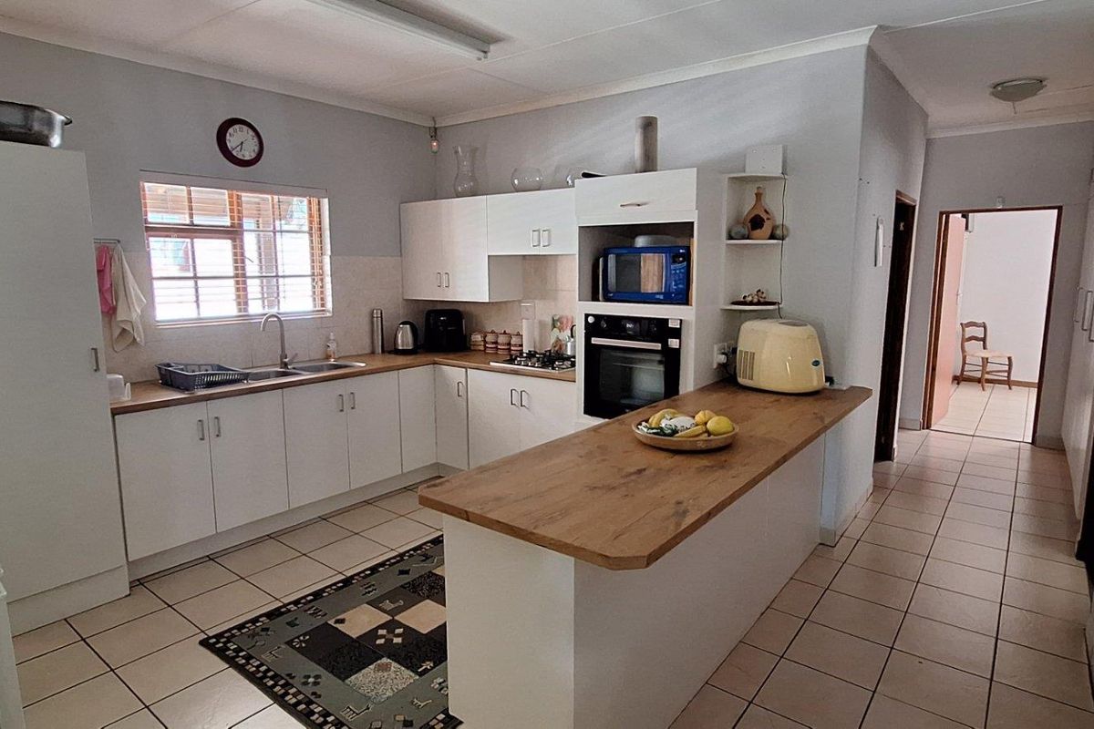 Functional kitchen featuring white cabinetry, wood-look countertops, built-in oven, and tiled flooring, offering a practical layout for daily meal preparation.