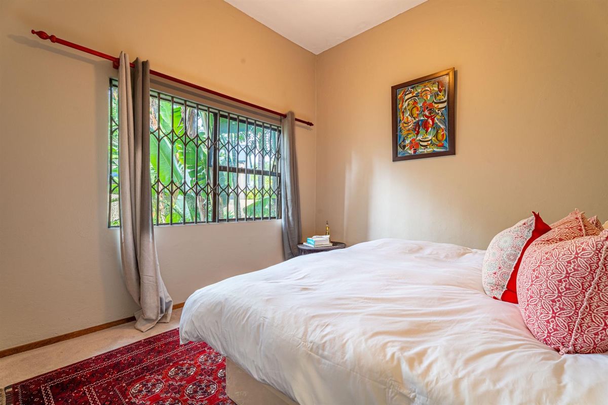 A bedroom featuring a window with integrated security bars, neutral wall finishes, and carpeted flooring.