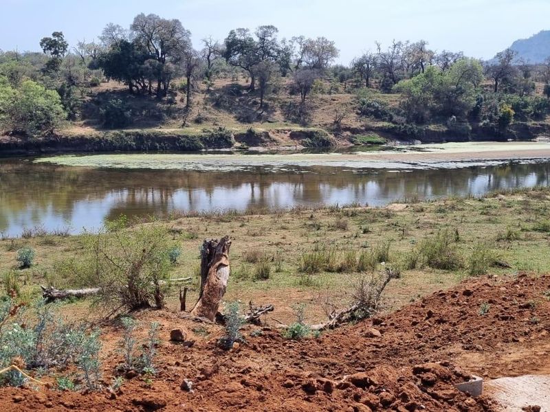 A scenic view of a river and natural landscape from the vacant residential property, featuring native vegetation and distant hills.