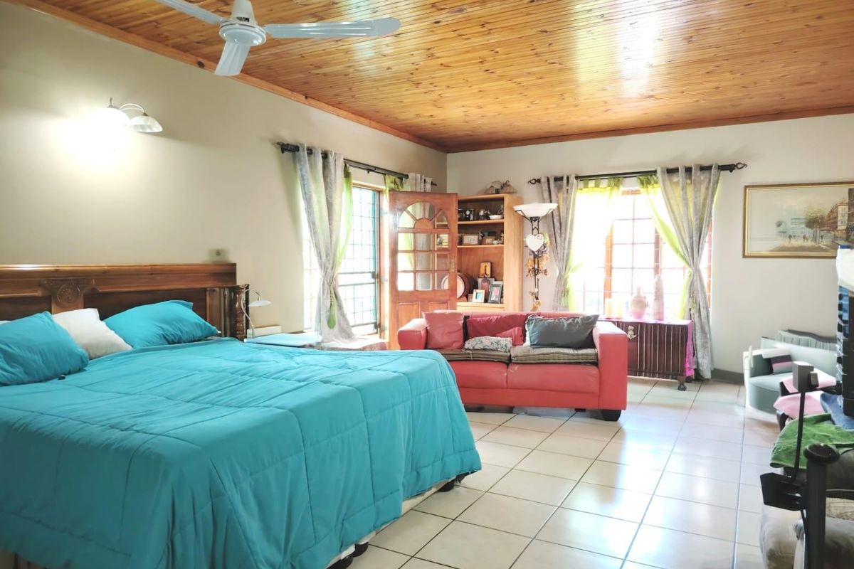 Spacious bedroom featuring a timber tongue and groove ceiling, ceiling fan, tiled flooring, and built-in shelving with natural light from multiple windows.