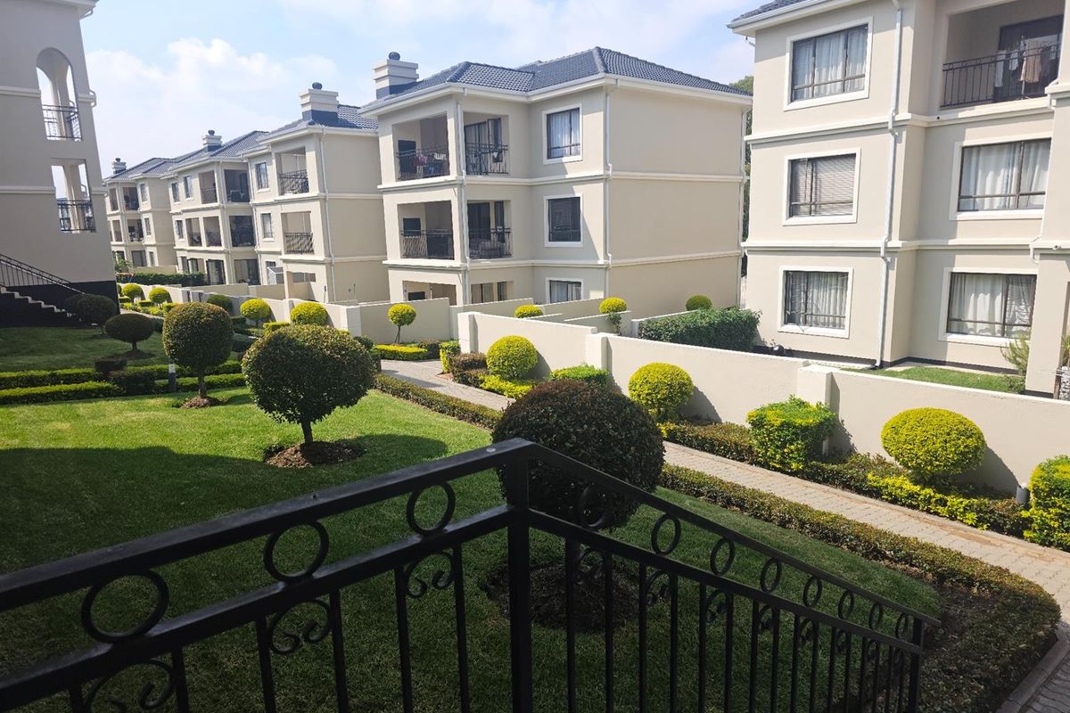 A view of the well-maintained apartment complex grounds featuring landscaped gardens, paved walkways, and multi-story residential buildings with balconies.