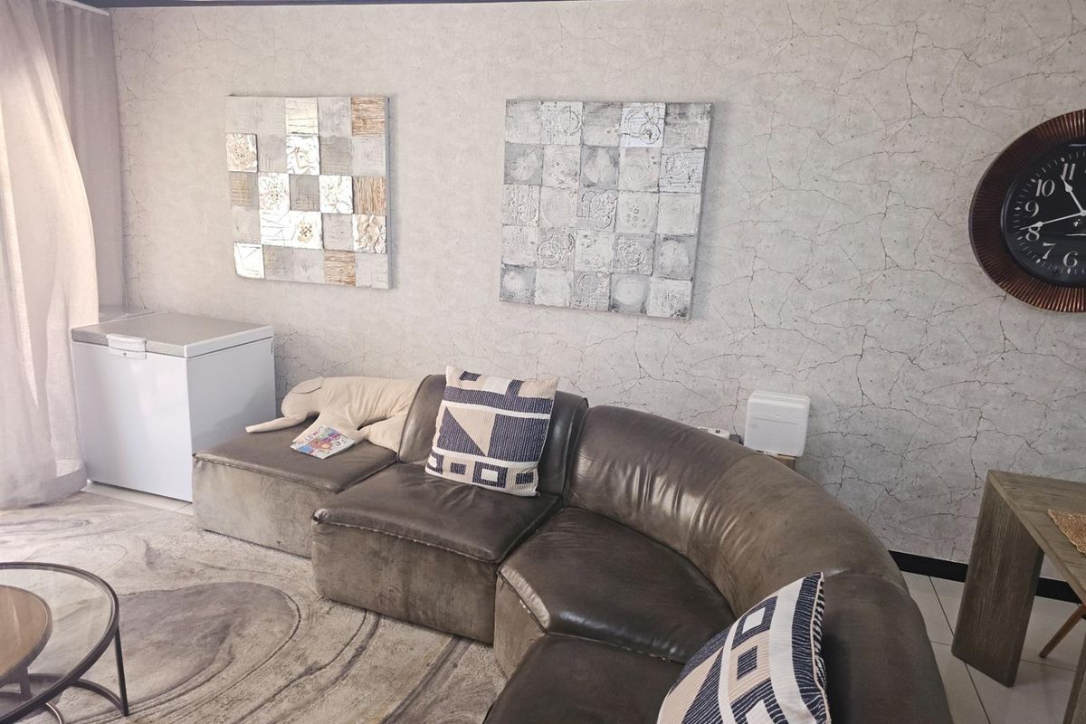A living room featuring textured wallpaper, tiled flooring, and a drop ceiling, providing a neutral base for interior design updates.