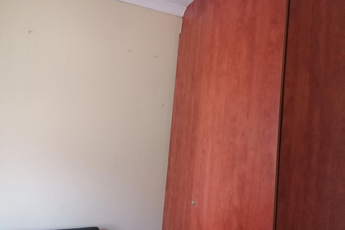 A bedroom corner featuring built-in wooden cabinetry with a plain painted wall finish.
