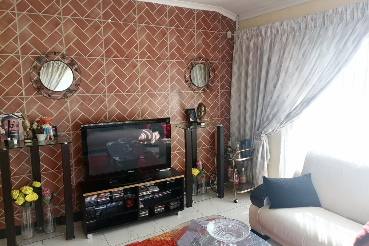 A living room featuring a distinctive herringbone-patterned tiled feature wall and tiled flooring, providing a functional and lived-in space.