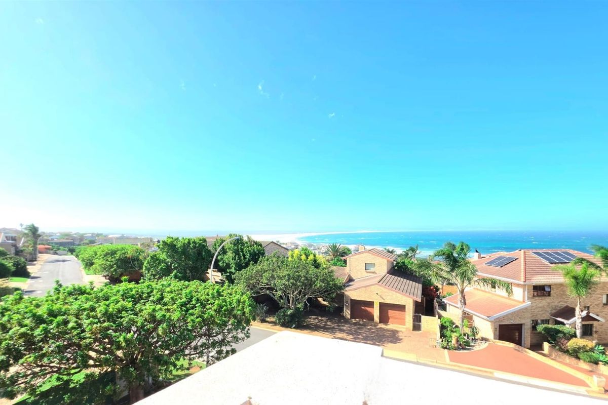 Elevated aerial view showcasing the surrounding residential neighborhood with a clear outlook towards the coastline and ocean.