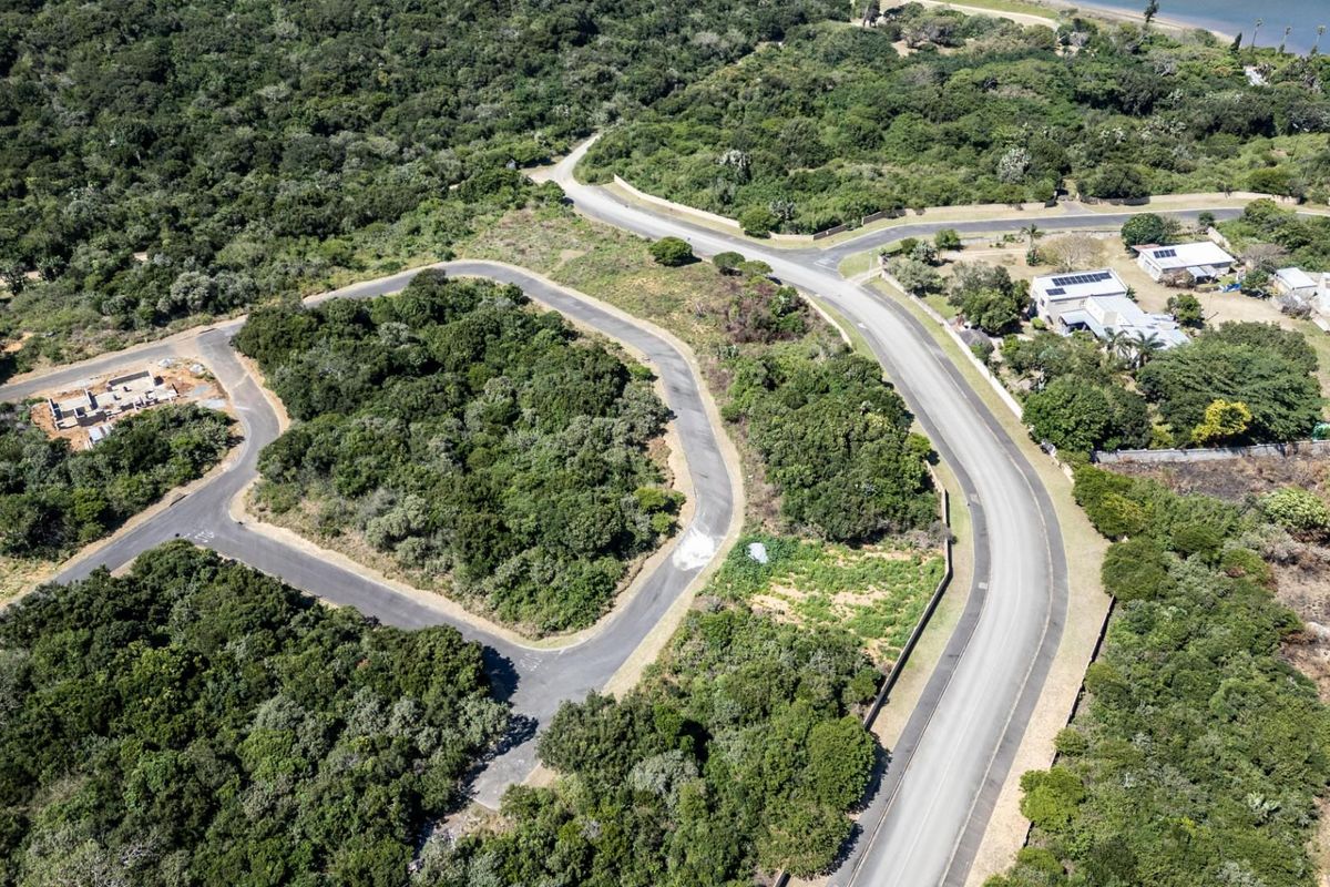 Aerial view of a residential vacant land plot situated within a developed estate, featuring established road access and surrounding natural vegetation.
