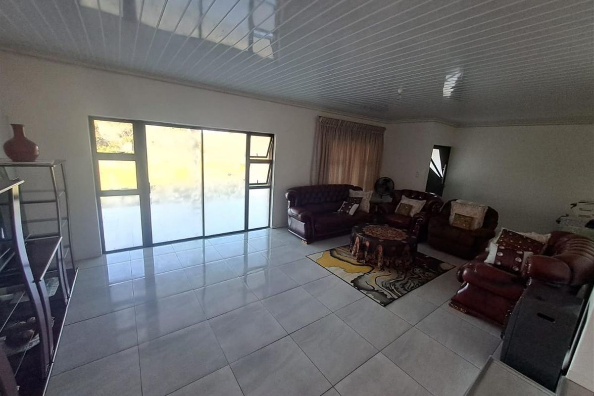 Spacious living room featuring large sliding glass doors for natural light, neutral tiled flooring, and a modern PVC panel ceiling.