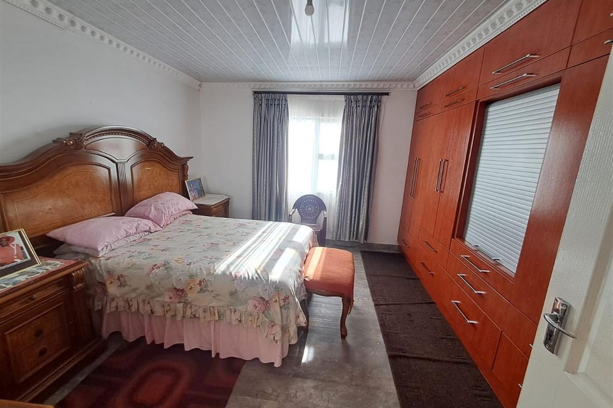 A bedroom featuring built-in wooden wardrobes, tiled flooring, and a coved ceiling, offering functional storage and a classic layout.