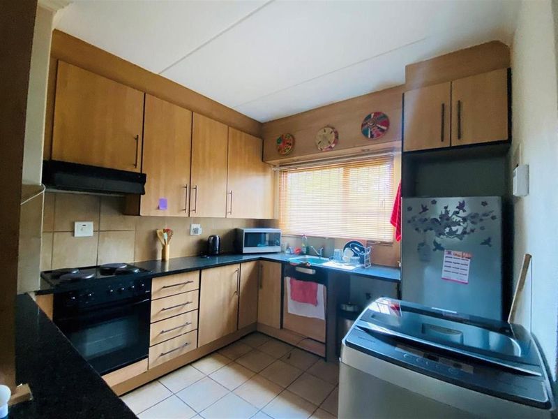 A functional kitchen featuring laminate cabinetry, black countertops, built-in oven, extractor fan, and tiled flooring, offering a practical layout for daily use.