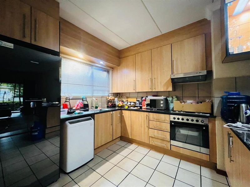 A functional kitchen featuring light wood-finish cabinetry, dark granite countertops, built-in oven, extractor fan, and tiled flooring.