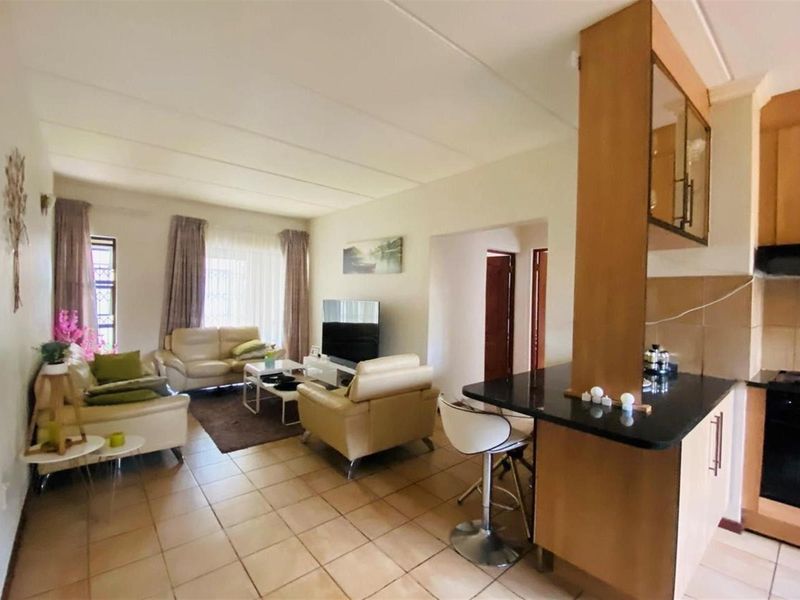 Open-plan living area featuring a functional kitchen with granite countertops, breakfast bar, and tiled flooring throughout the combined lounge and dining space.