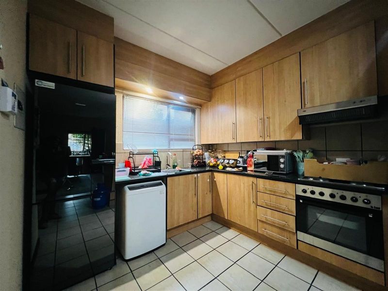 A functional kitchen featuring laminate cabinetry, black granite countertops, built-in oven, hob, extractor fan, and tiled flooring.