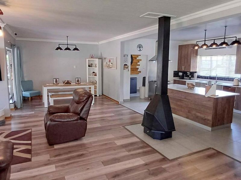 Spacious open-plan living area featuring a modern kitchen with island, laminate flooring, and a central freestanding fireplace, creating a warm and functional home layout.