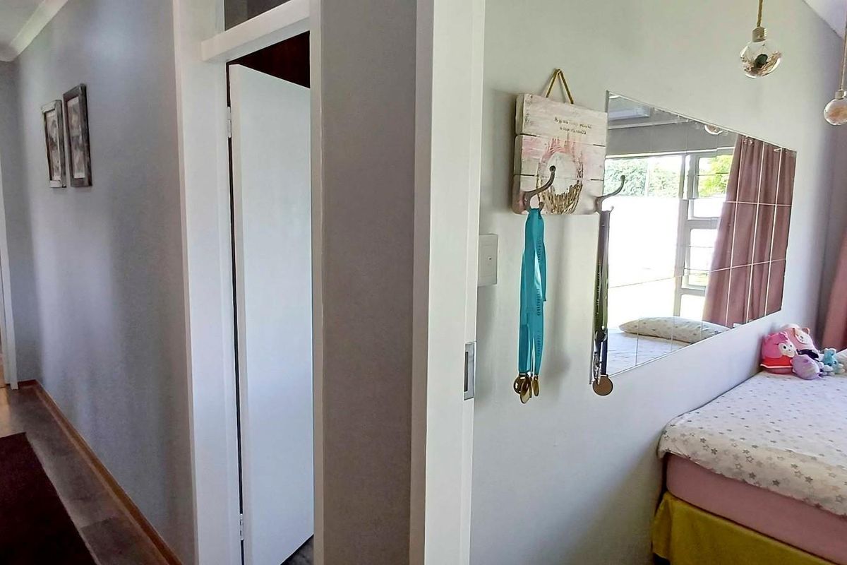 A view from a hallway looking into a bedroom featuring laminate flooring and neutral wall finishes.