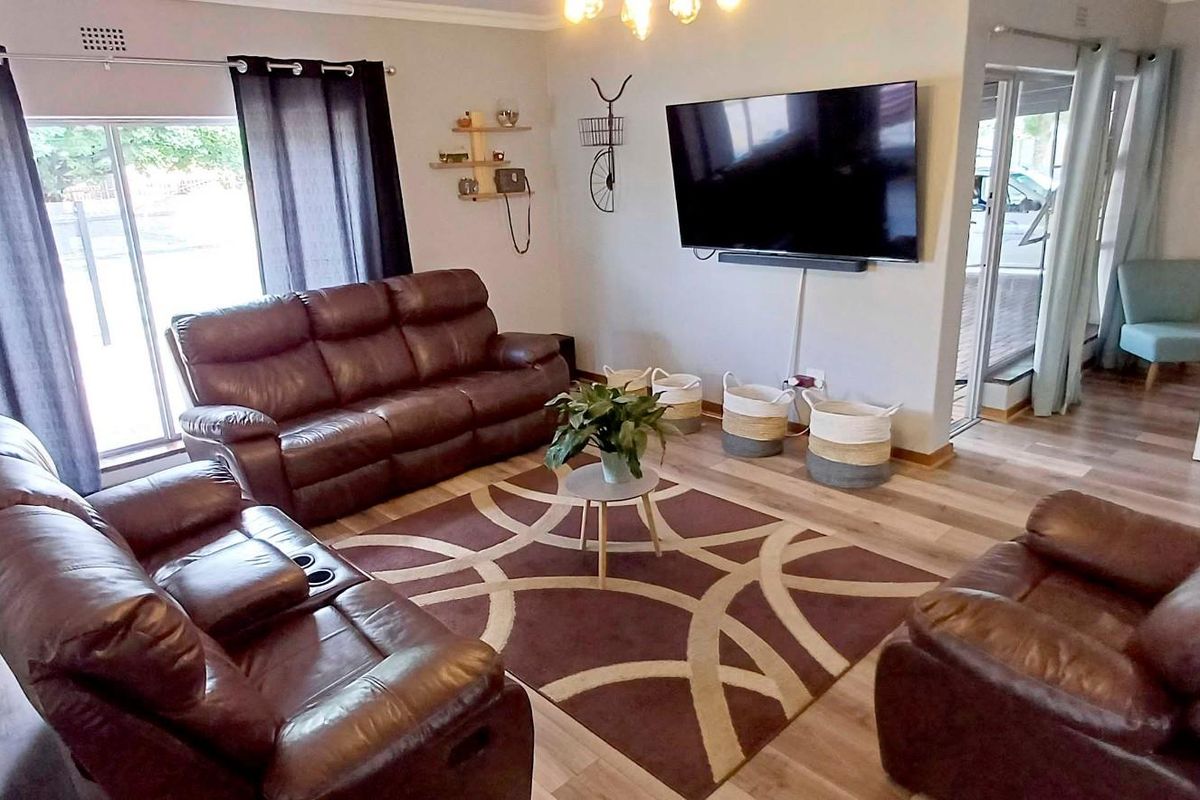A well-maintained living room featuring durable laminate flooring, neutral wall tones, and large sliding glass doors that provide ample natural light.