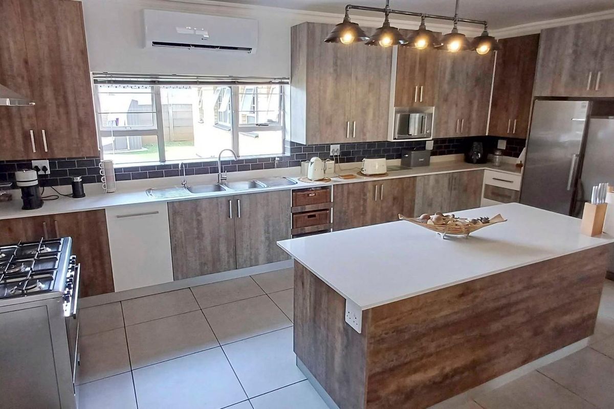 Modern kitchen featuring wood-look cabinetry, a central island with stone countertop, gas stove, subway tile backsplash, and tiled flooring.