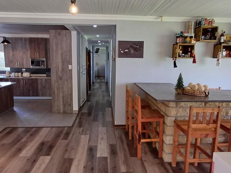 Spacious open-plan living area featuring a modern kitchen with wood-look cabinetry, a stone-clad breakfast bar, and a contemporary freestanding fireplace.