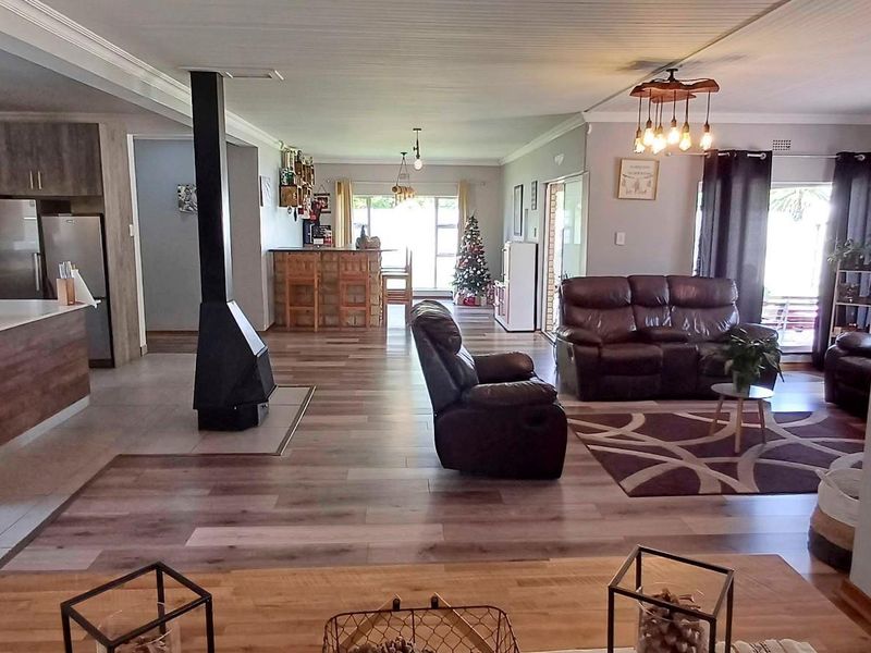 Spacious open-plan living area featuring a modern kitchen with island, laminate and tiled flooring, and a central freestanding fireplace.