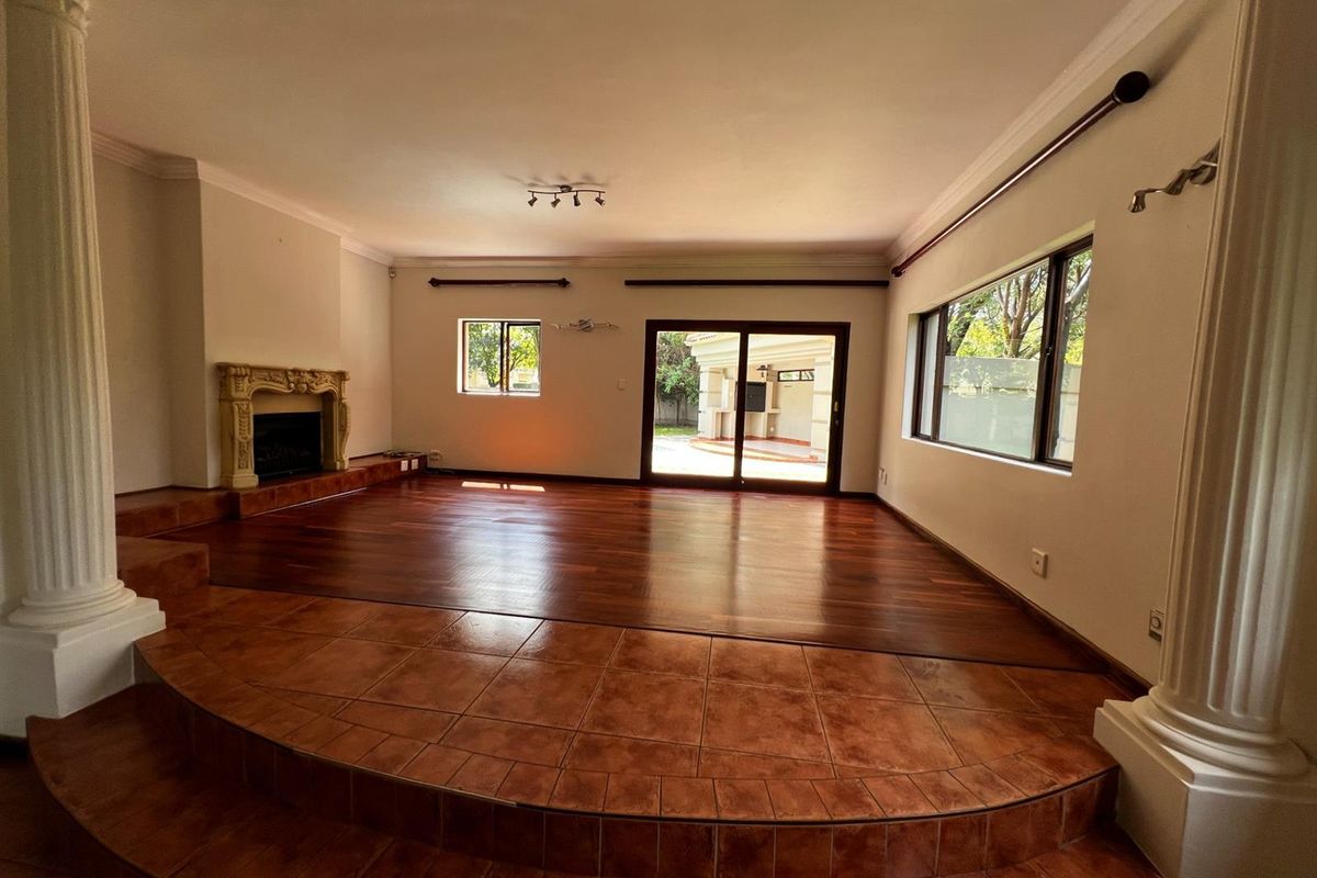 Spacious living room featuring a raised tiled platform, hardwood flooring, a decorative fireplace, and sliding glass doors leading to the outdoor area.