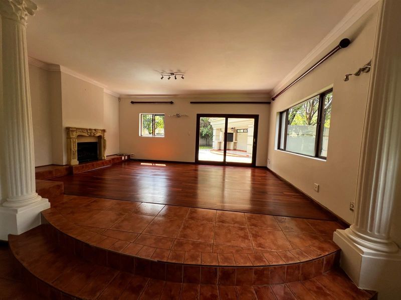 Spacious living room featuring a raised tiled platform, hardwood flooring, a decorative fireplace, and sliding glass doors leading to the outdoor area.